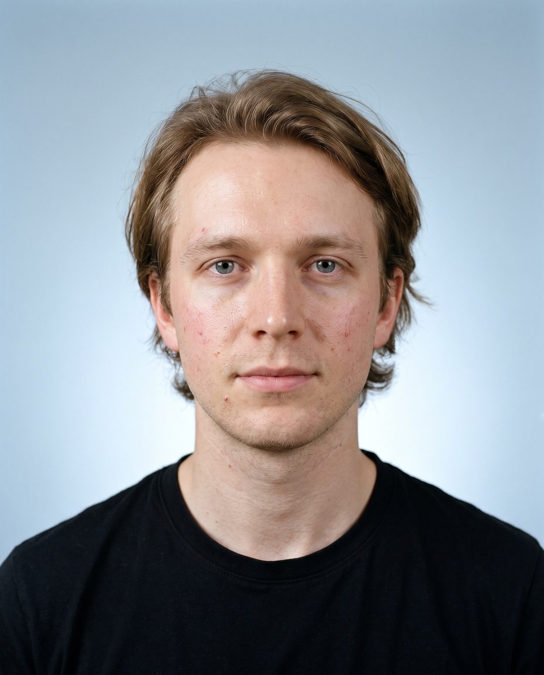 KI-Visualisierung, Ausgangsbild: Mann mit herausgewachsenem hellbraunem Haar und ungleichmäßigem Bartschatten, frontal vor graublauem Hintergrund