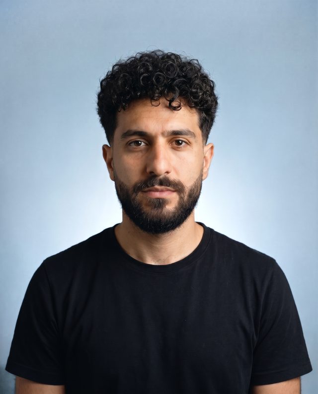 KI-Visualisierung, Projektion: derselbe Mann mit definiertem Lockenschnitt, Low Taper Fade und kurz geformtem Vollbart, frontal vor graublauem Hintergrund